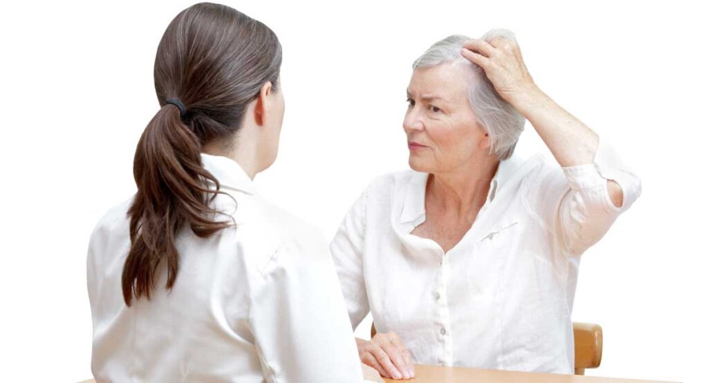 Mujer mayor que muestra su adelgazamiento del cabello o pérdida de cabello a su doctora