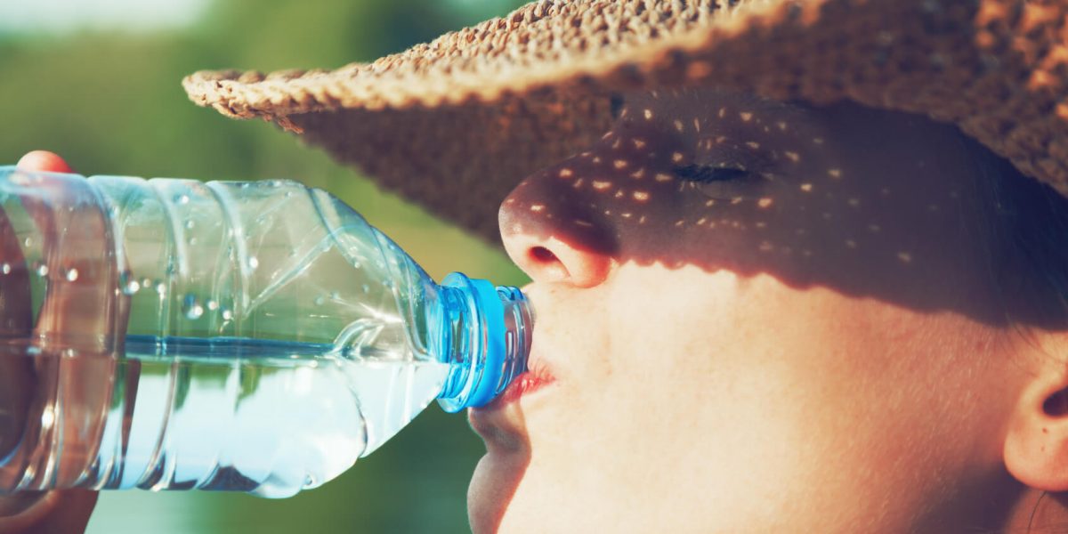 Chica-bebiendo-agua-con-sombrero-proteccion-del-sol